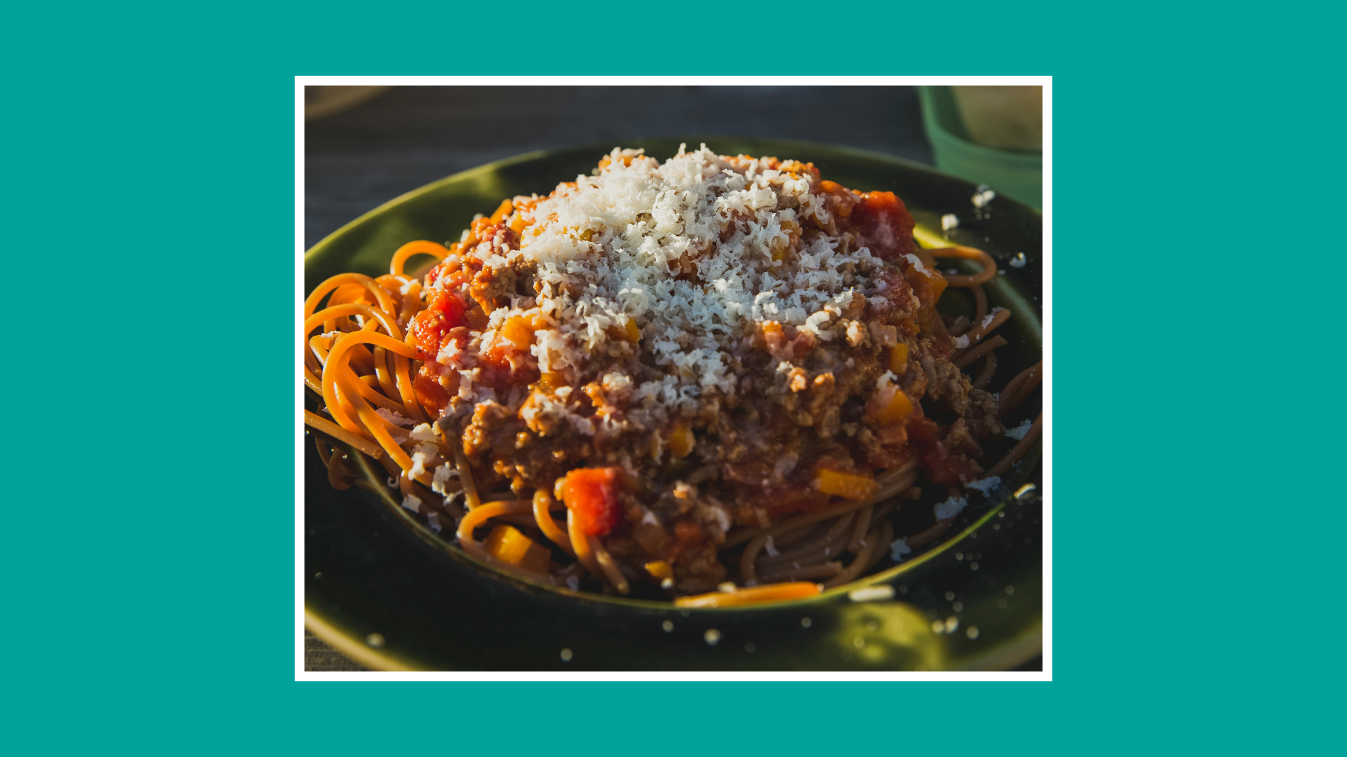 “Plate of spaghetti topped with rich beef bolognese sauce and grated cheese.”