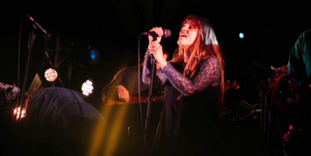 Performer singing into microphone on stage