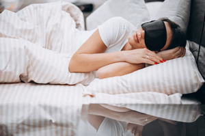 Person asleep in bed with sleep mask on