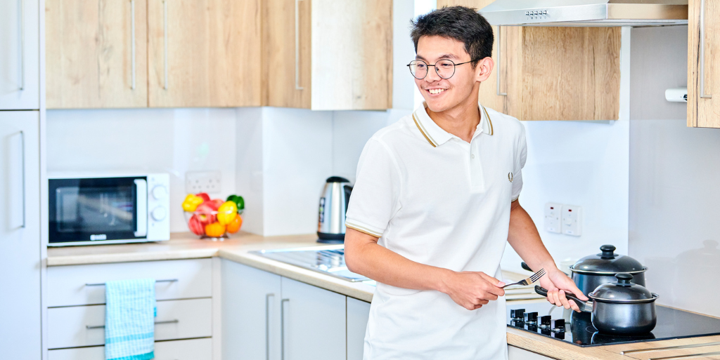 Student cooking at hob in accommodation