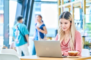 Student looking at laptop with cup of coffee