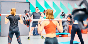 Students using barbells facing instructor