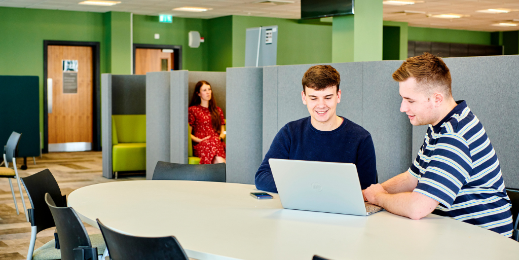 Two students sat a table around laptop