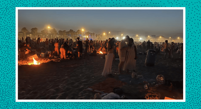 Image of crowd having fires on the beach at night 