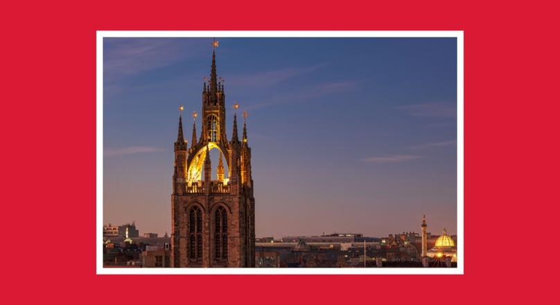 Illuminated cathedral tower at dusk overlooking Newcastle city centre.