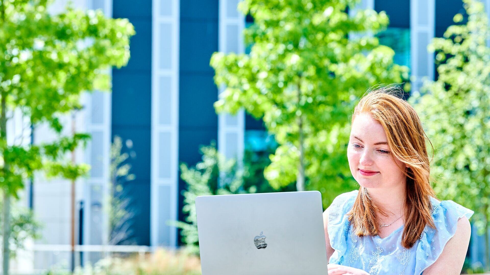 student working on a laptop, outside