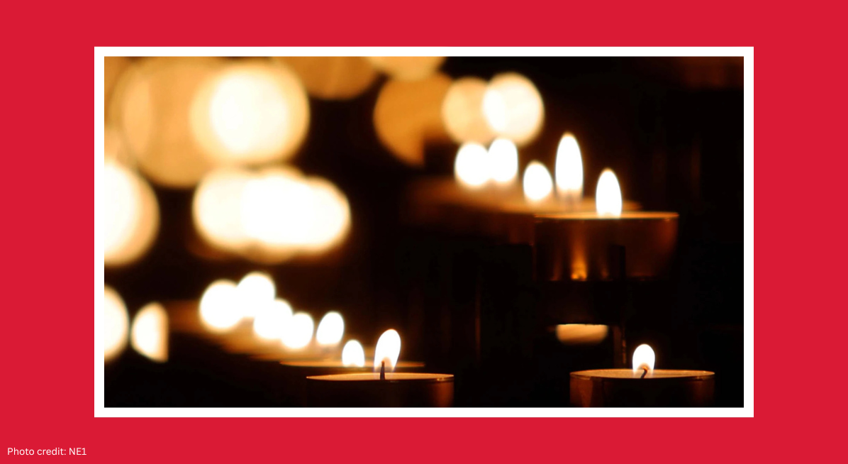 Rows of lit candles creating a warm, atmospheric scene inside a dark space