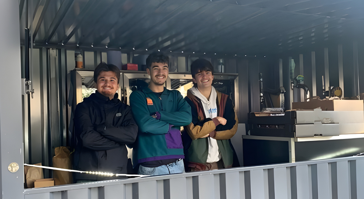 Three volunteers working in a shipping container outside the Students Union