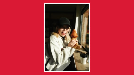 holding a croissant in a sunlit café