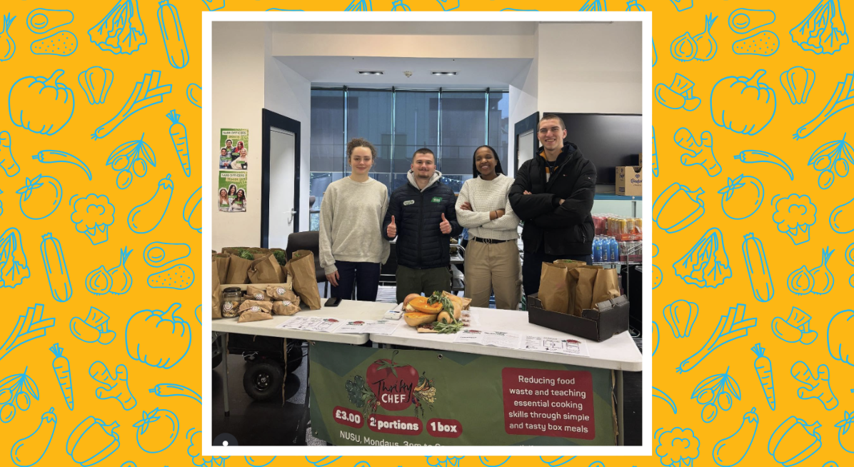 image of four volunteers in front of a table of produce and bags with a banner that says thrifty chef, £3, two portions, one box