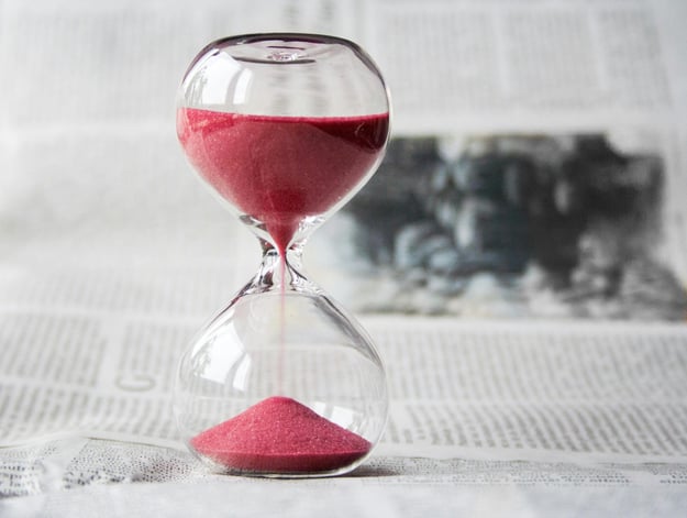 hourglass with red sand on a newspaper