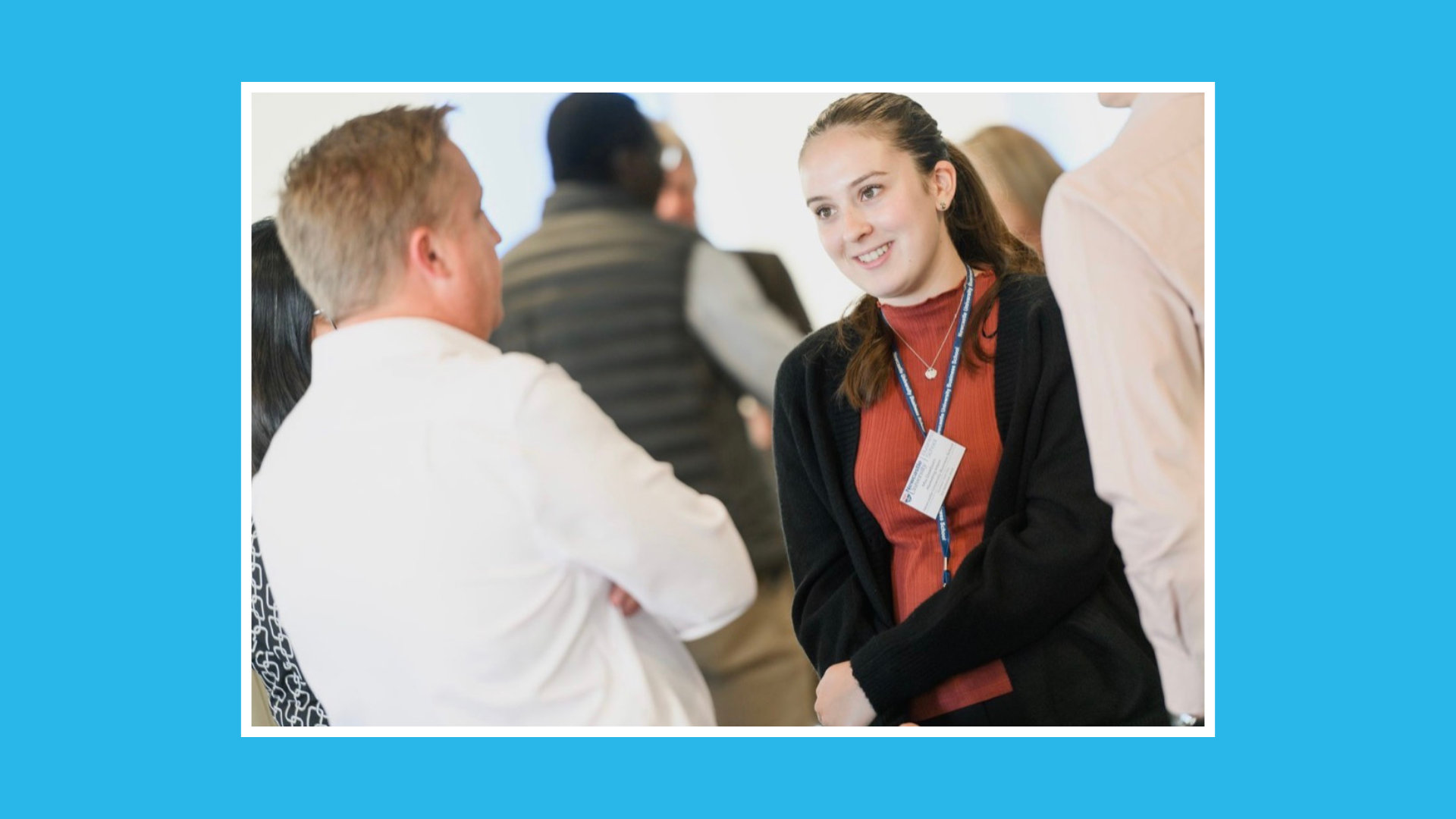 Mia on her placement wearing a Newcastle University lanyard speaking with colleagues at a networking event.